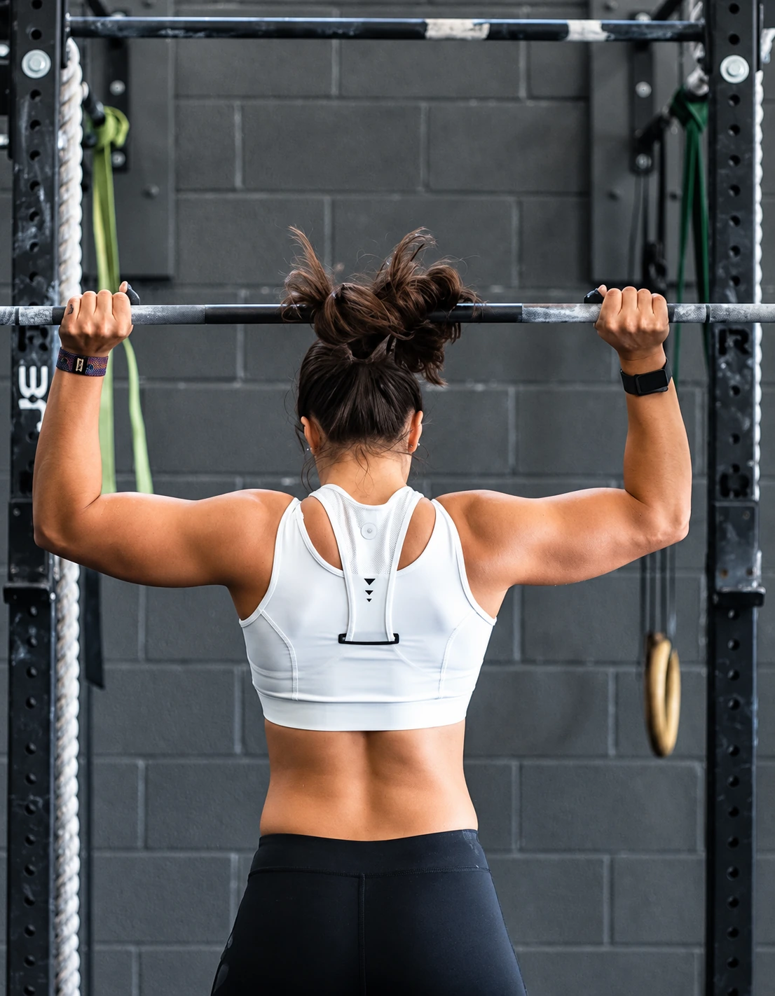 Female athlete gripping a barbell on a rack, seen from behind, representing post-exertion autonomic rebound and nervous system recovery