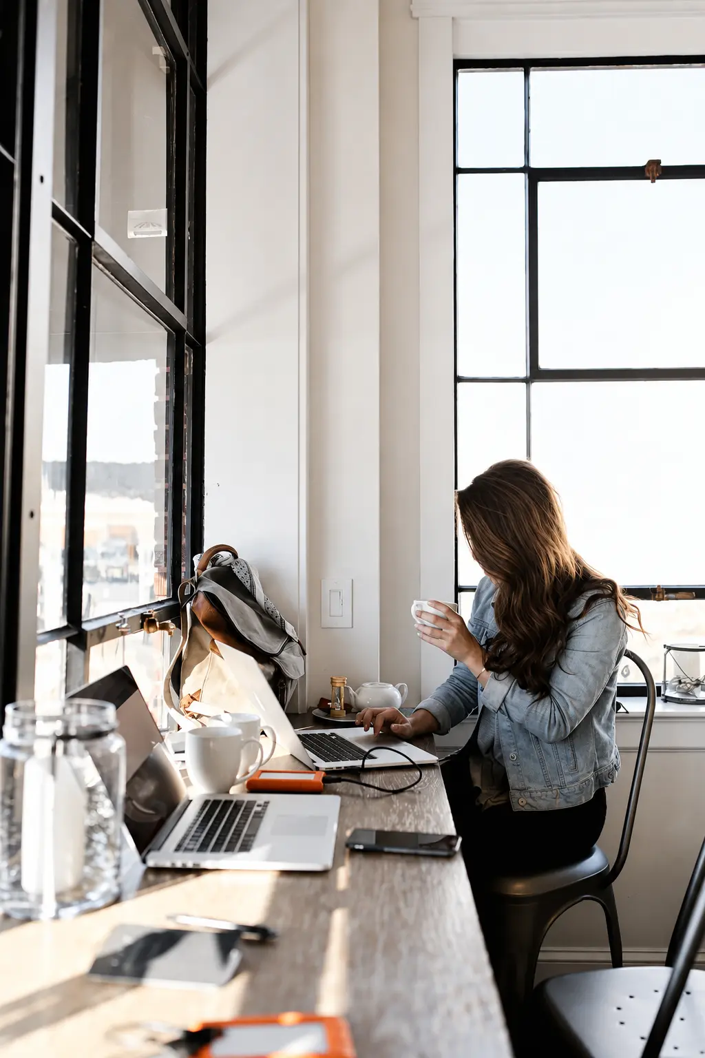 Professional working on a laptop by a window, representing cognitive fatigue and the hidden biological cost of sustained performance.